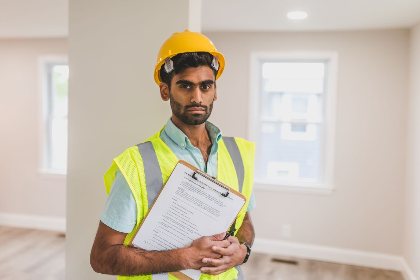 Inspector in a hard hat reviewing a clipboard on site